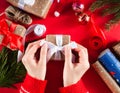 Female hands tying a bow on gift box. Preparation for holidays. Christmas or New Year flatlay. Top view. Close-up Royalty Free Stock Photo