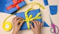 Female hands tying a yellow silk bow on a blue gift box, preparing a surprise Royalty Free Stock Photo