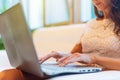 Female hands typing on keyboard. Cropped photo of a young woman holding laptop her knees and working. Royalty Free Stock Photo