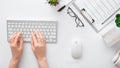 Female hands typing on keyboard at white table office workspace. Flat lay woman hands on white table desk use pc Royalty Free Stock Photo