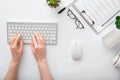 Female hands typing on keyboard at white table workplace. Home office workspace with keyboard mouse glasses. Flat lay Royalty Free Stock Photo