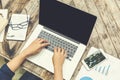 Female hands typing on laptop keyboard with smart phone on wooden table Royalty Free Stock Photo