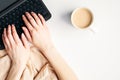 Female hands typing a text on laptop keyboard top view. Flat lay modern minimal feminine workspace with blanket, coffee cup and Royalty Free Stock Photo
