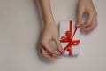 Female hands untie the red ribbon on a gift box on a light background. Christmas and New Year or season greetings. Selective focus Royalty Free Stock Photo