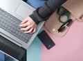 Female hands use a laptop on the background of a bag, smartphone, smart bracelet and other gadgets and accessories. Top view Royalty Free Stock Photo