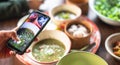 Female hand use a smartphone to taking photo with the local food from the top view. Royalty Free Stock Photo