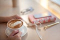 Female hands using mobile phone for organising schedule while drinking latte during the coffee break