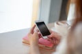 Female hands using mobile phone for organising schedule while drinking latte during the coffee break