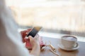 Female hands using mobile phone for organising schedule while drinking latte during the coffee break