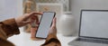 Female hands using mock up smartphone while sitting at worktable with mock up laptop in home office Royalty Free Stock Photo