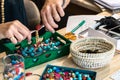 Female hands using pliers to make handmade bijouterie with little balls and stones