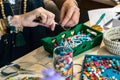 Female hands using pliers to make handmade bijouterie with little balls and stones