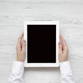 Female hands using tablet over white wooden surface, top view. From above, overhead, flat lay Royalty Free Stock Photo