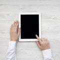 Female hands using tablet on a white wooden surface, top view. From above, overhead, flat lay Royalty Free Stock Photo