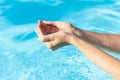 Female hands with vacation blue nail design. Glitter aquamarine nail polish manicure. Female hands in a blue pool water