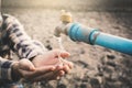 Female hands want to drink some water in faucet on crack ground