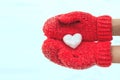 Female hands in warm red crocheted mittens with snowy heart. Whi Royalty Free Stock Photo