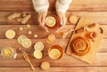 Female hands in warm sweater holding cup of tea with lemon, honey, ginger root ingredients and sweet cinnamon bun on Royalty Free Stock Photo