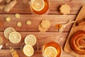 Female hands in warm sweater holding cup of tea with lemon, honey, ginger root ingredients and sweet cinnamon bun on Royalty Free Stock Photo