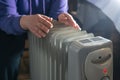 Female hands warming on oil heater at home close up. Cold winter with radiator. Heating season Royalty Free Stock Photo