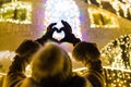 Female hands wearing gloves showing heart shape. Bokeh christmas new year decoration in the background Royalty Free Stock Photo