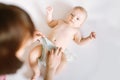 Female hands wearing pants for baby, a little kid lying on the bed nanny change diaper after bath, mother and baby Royalty Free Stock Photo