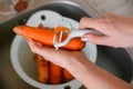 Female hands clean carrots with a vegetable peeler.Cleaning vegetables