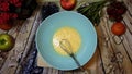 female hands whip eggs in bowl on the kitchen table by the window, top view