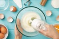 Female hands whipping egg whites cream with mixer in the glass bowl on blue pastel wooden table. Royalty Free Stock Photo