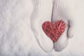 Female hands in white knitted mittens with a entwined vintage romantic red heart on a snow. Love and St. Valentine concept. Royalty Free Stock Photo