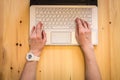 Female hands on white on laptop with black cover on wooden surface top view Royalty Free Stock Photo