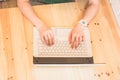 Female hands on white on laptop with black cover on wooden surface top view Royalty Free Stock Photo