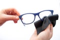 Female hands wiping spectacles with a microfiber fabric