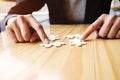 Female hands on a wooden office desk pick puzzle Royalty Free Stock Photo