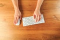 Female hands working with modern white keyboard and mouse on wooden background, top view  - Image Royalty Free Stock Photo
