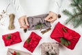 Female hands wrap a gift. Japanese wrapping cloth Furoshiki. Silk cloth with green fir and pine cones. Royalty Free Stock Photo