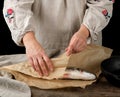 female hands are wrapped in brown paper whole fresh sea bass fish Royalty Free Stock Photo