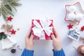 female hands are wrapping a Christmas present on a white table with cute Christmas tree toys. Royalty Free Stock Photo