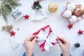 female hands are wrapping a Christmas present on a white table with cute Christmas tree Royalty Free Stock Photo
