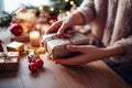 Female hands wrapping christmas present on wooden table. Woman decorating christmas tree at home. Selective focus Royalty Free Stock Photo