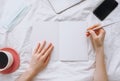 Female hands write in a notebook at home on the bed.