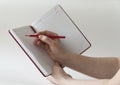 Female hands write a red pencil in a notebook Royalty Free Stock Photo