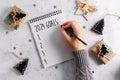 Female hands writing goals 2024 in a notebook. Festive decoration on table. Flat lay. New Year\'s plans