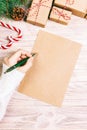 Female hands writing a letter to Santa Claus. Christmas gifts with christmas decoration on a wooden background. View from above. Royalty Free Stock Photo