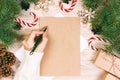 Female hands writing a letter to Santa Claus. Christmas gifts on a wooden background. View from above. Toned Royalty Free Stock Photo