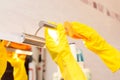 Female hands with yellow rubber protective gloves cleaning cleaning lamp with orange cloth.