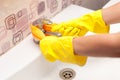 Female hands with yellow rubber protective gloves cleaning tap with orange cloth Royalty Free Stock Photo