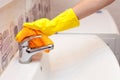 Female hands with yellow rubber protective gloves cleaning water tap with orange cloth Royalty Free Stock Photo