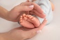 Female hands of young mother holding her newborn baby feet, closeup image with blur baby in background Royalty Free Stock Photo