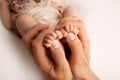 Female hands of young mother holding her newborn baby feet, closeup image with blur baby in background Royalty Free Stock Photo